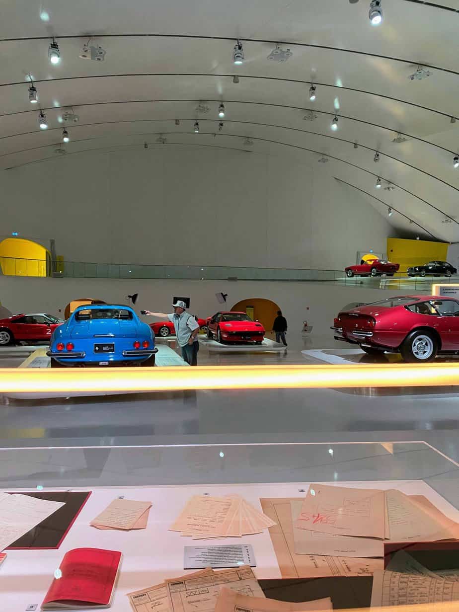 Historic documents and cars inside the futuristic Enzo Ferrari Museum in Modena, Italy.