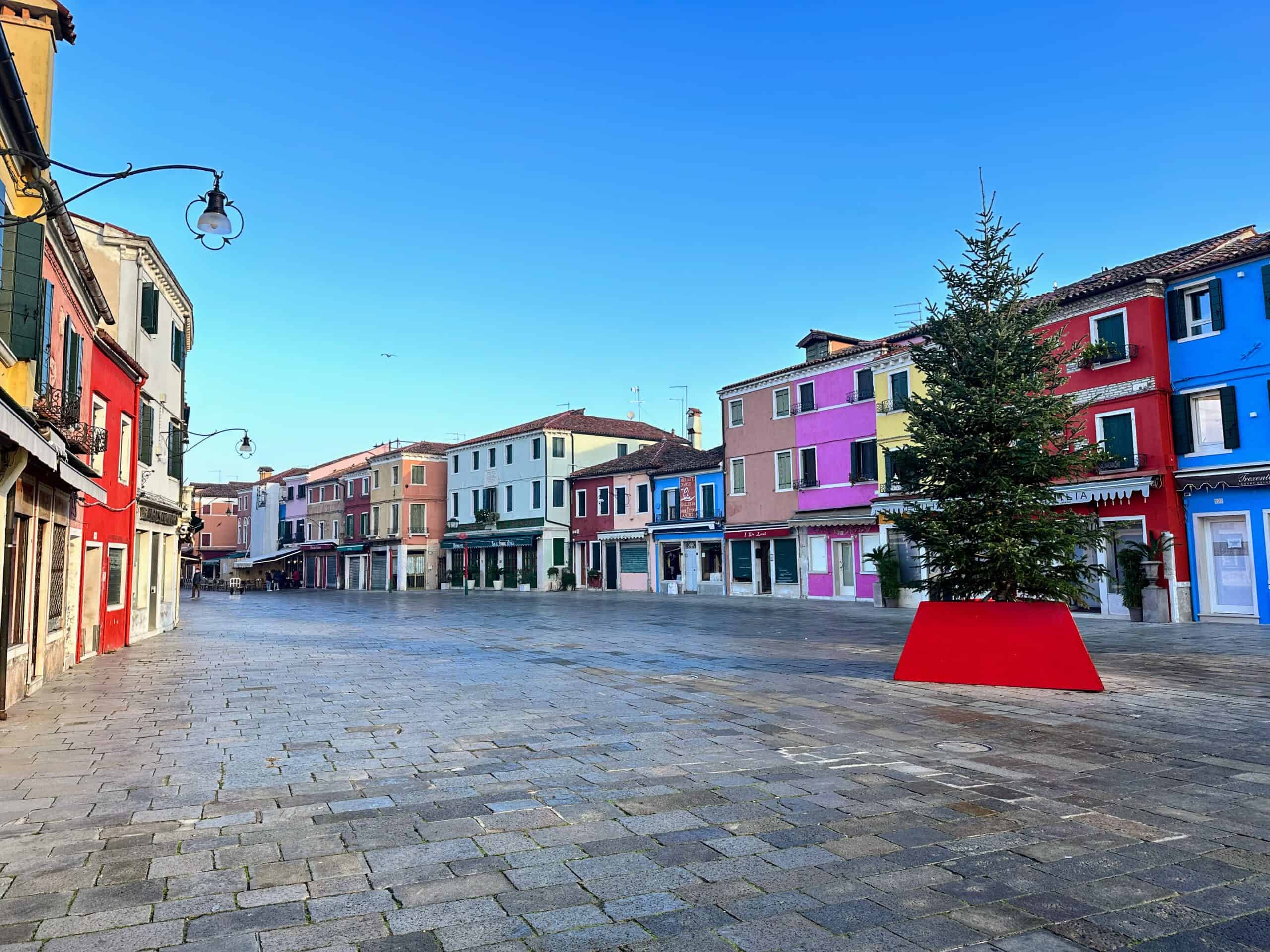An empty piazza on Burano Island in Venice. There's a Christmas tree set up on the right.