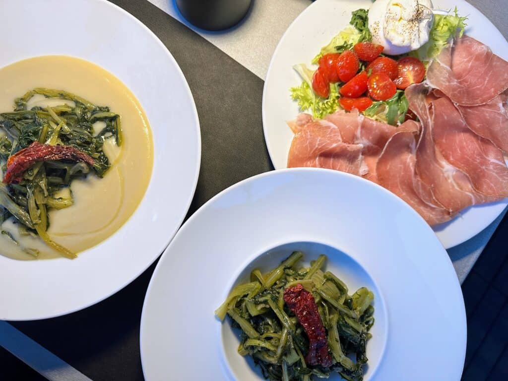 Soup, vegetables, cured meats, and cheese on a table in Matera, Italy.