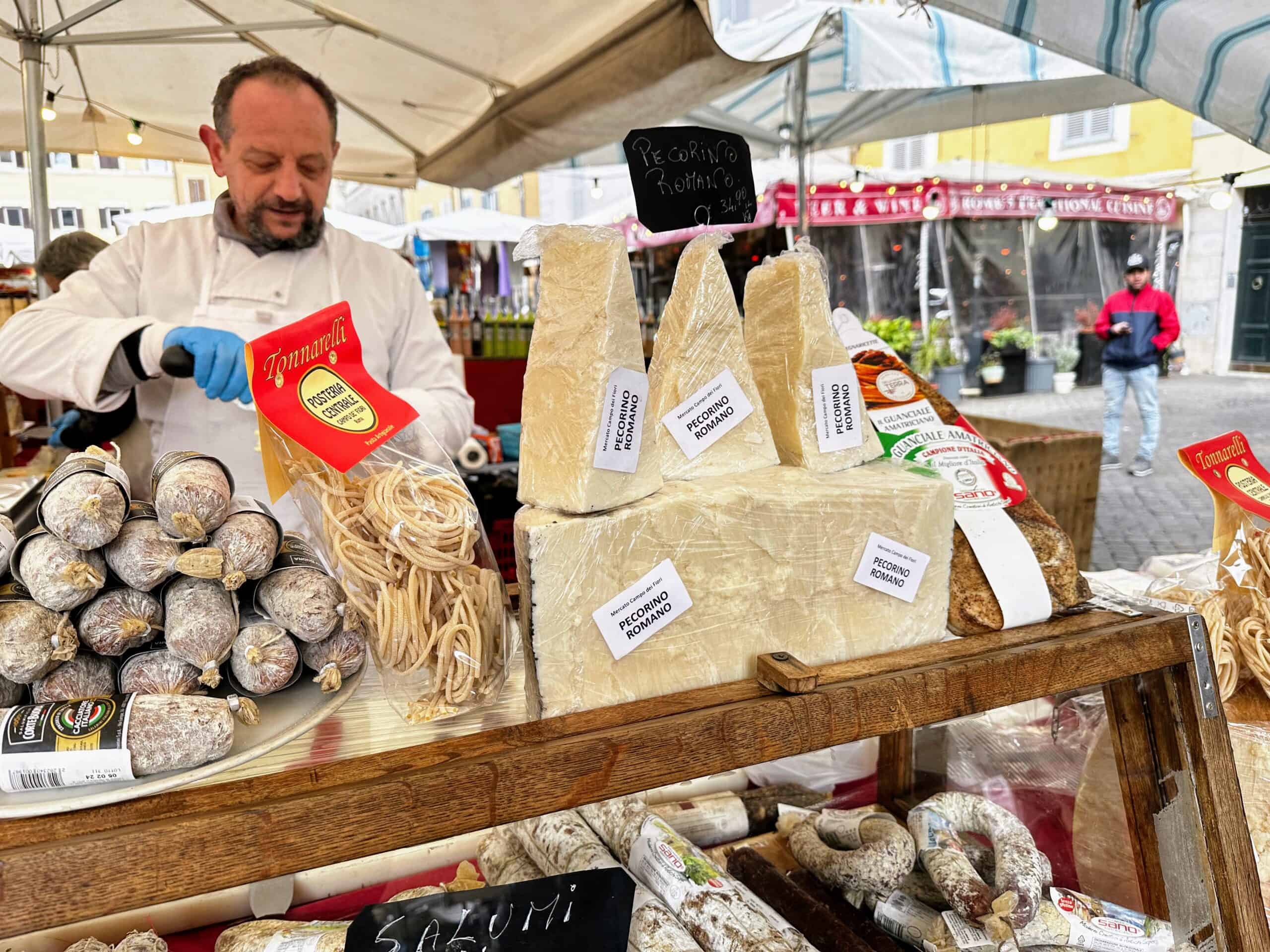 Vendor sells cheese and cured meats at a stand at the Campo de' Fiori Market in Rome.