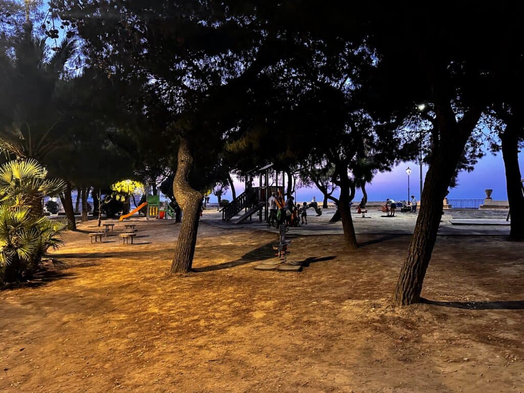 Playground at dusk in Trani, Italy. Umbrella pines surround the play area.
