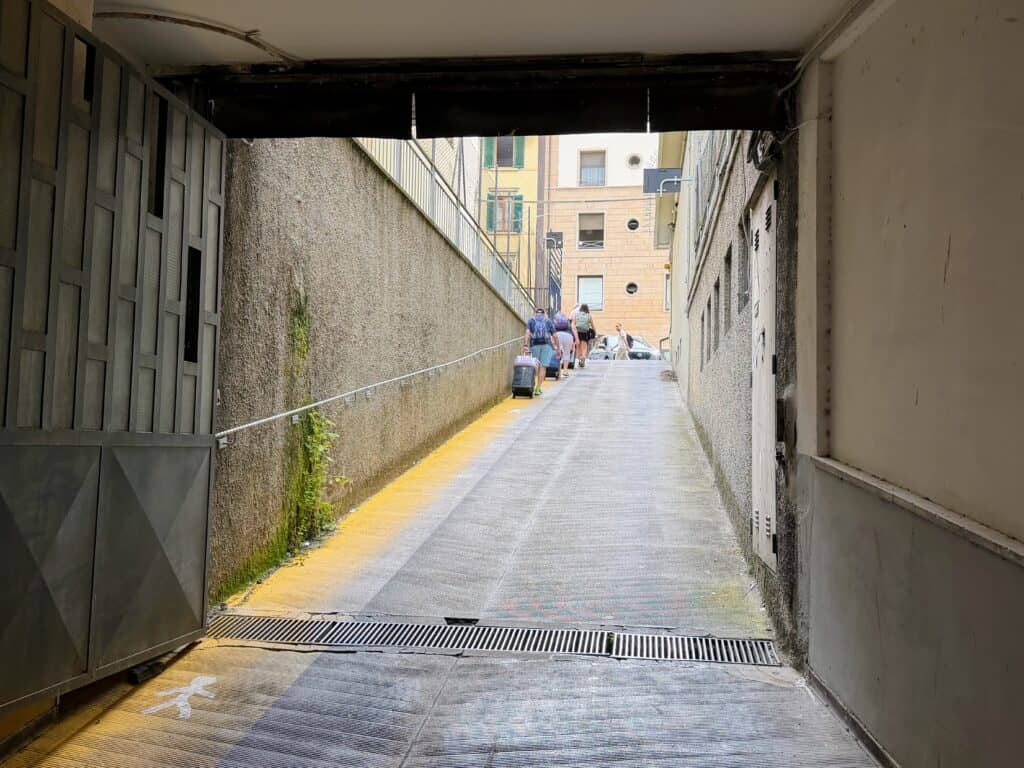 View from inside a garage as people with suitcases walk up the entrance to the city streets of Florence, Italy.
