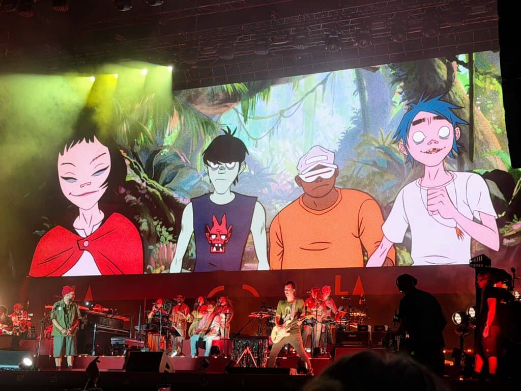 Four cartoon characters fill the screen above the concert stage where the band the Gorillaz plays for fans in Tuscany, Italy.