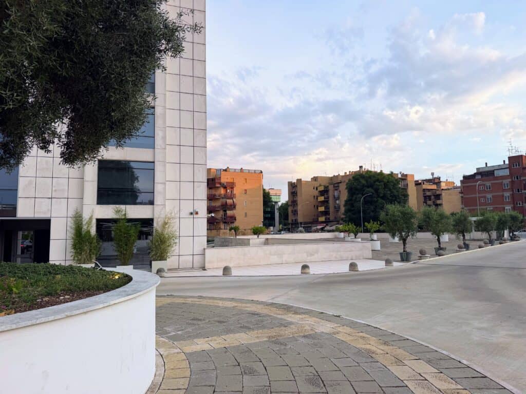 Outside the entrance of Precise House Mantegna Rome, looking across paved property toward multi-story apartment buildings.