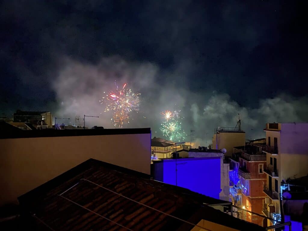 Colorful fireworks explode over rooftops in Taormina, Italy on New Year's Eve.