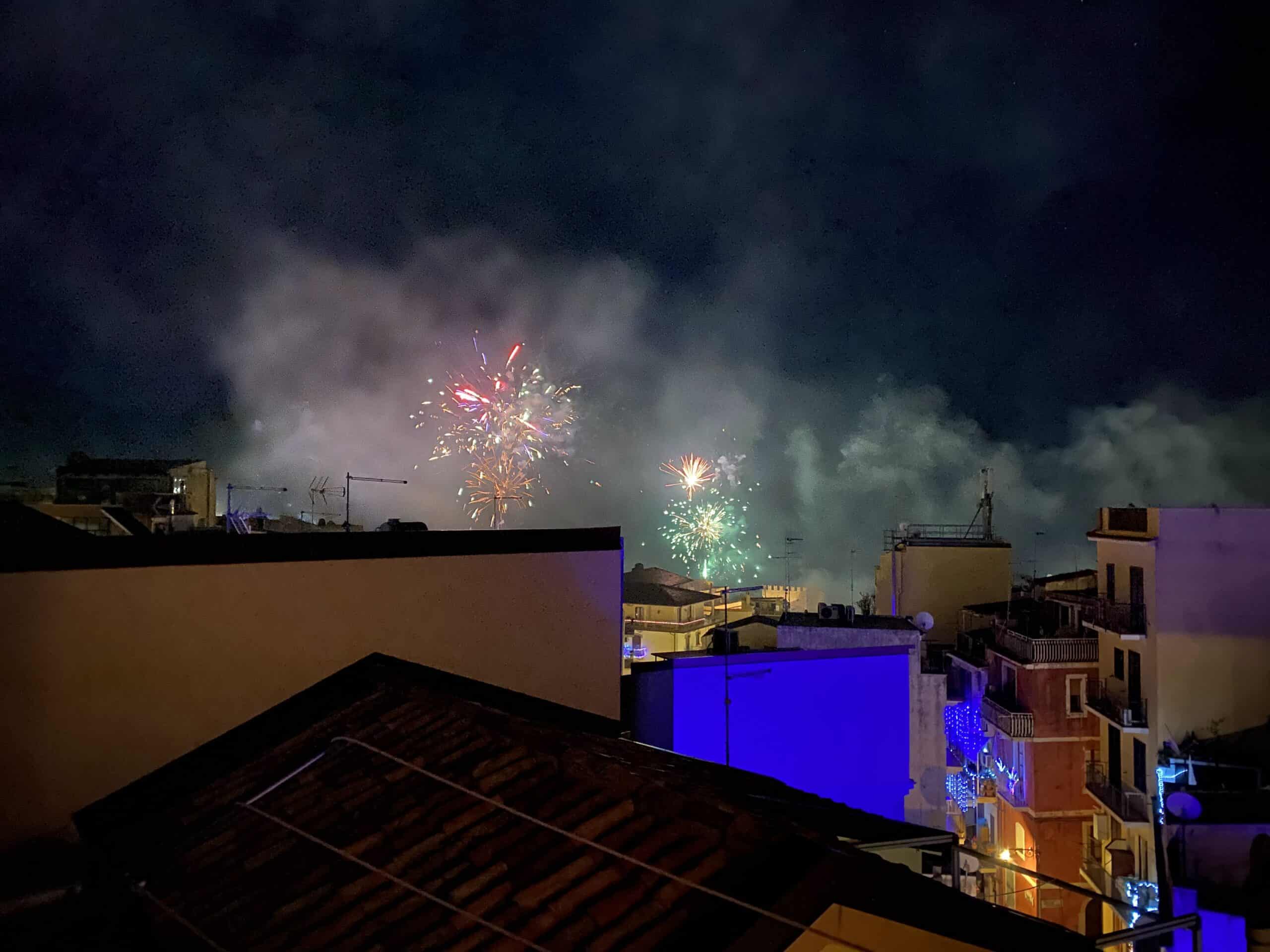 Colorful fireworks explode over rooftops in Taormina, Italy on New Year's Eve.