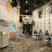 Entrance to Pinsotti restaurant in Monopoli, Puglia. People eating at tables in front. Lights hanging above, sunflower chains hanging form wall. Cobblestone ground.